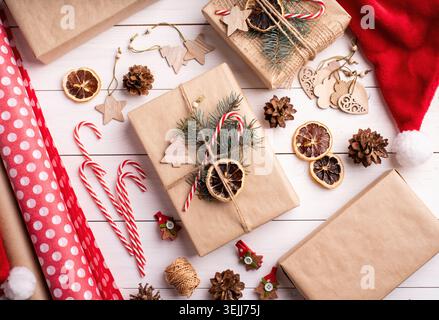 Gift boxes wrappaed in craft paper decorated with pine cones, candy canes and fir tree branches top view flat lay Stock Photo