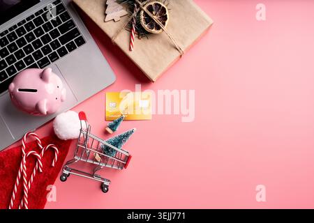 Top view of laptop, christmas decorations and piggy bank on pink background. Christmas online shopping Stock Photo