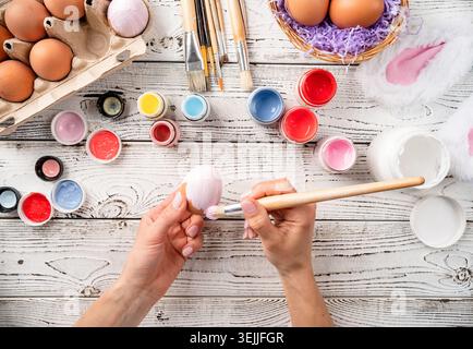 Female hands coloring easter eggs with pastel paints, top view flat lay Stock Photo