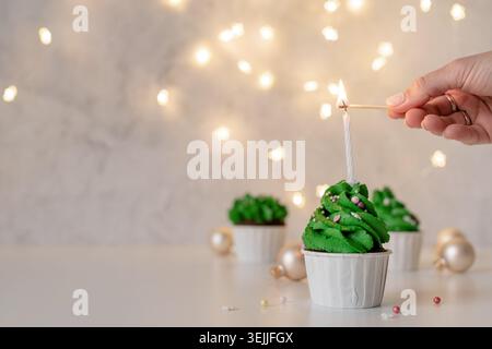 Christmas tree shaped cupcakes, surrounded with festive decorations and lights on the background Stock Photo