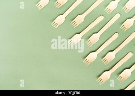 Disposable wooden forks top view on green background with copy space Stock Photo