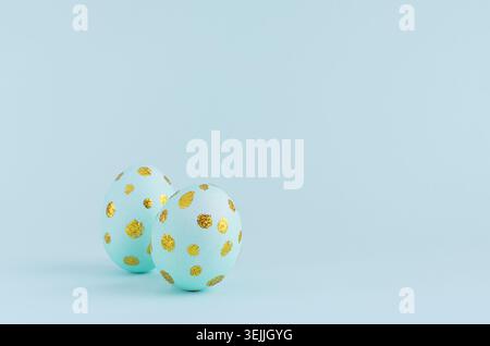 Elegant easter eggs with gold dots on blue background, copy space. Stock Photo