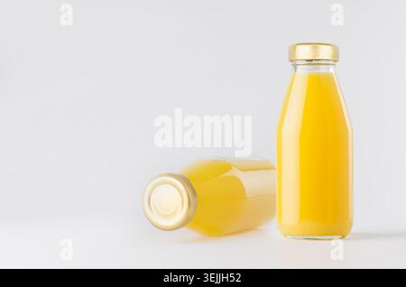 Orange yellow juices in glass bottles with gold empty cap for label mock up on white background with copy space, template for pa Stock Photo