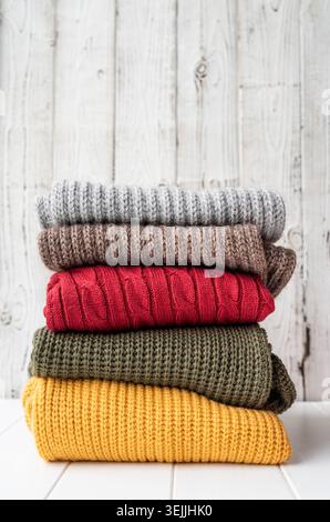 Stack of autumn warm sweaters on white wooden background Stock Photo