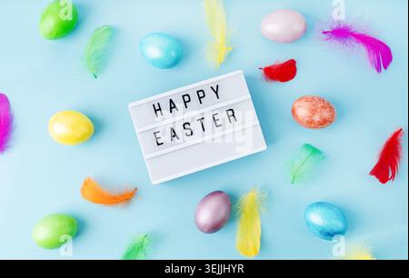 Top view Happy Easter light box decorated with bright colored eggs and feathers Stock Photo