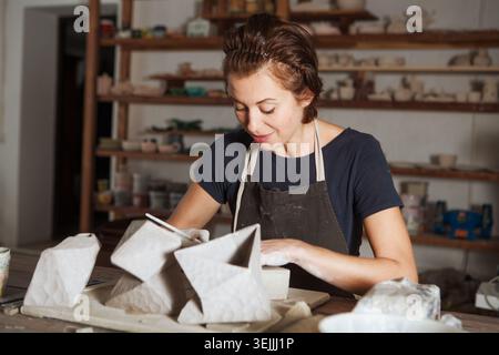 Adult woman make pottery at table in workshop Stock Photo
