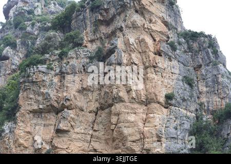 Steep Limestone Canyon Cliff Wall with Natural Cavities and Rugged Rock Layers Stock Photo