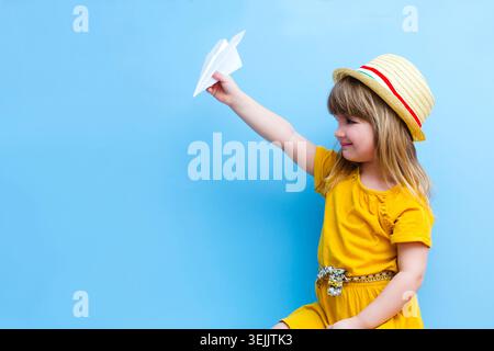Child girl playing with paper plane on a blue background Stock Photo