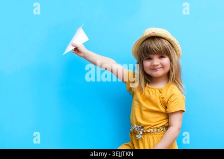 Child girl playing with paper plane on a blue background Stock Photo