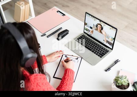 Young latin woman in black headphones teaching english online Stock Photo