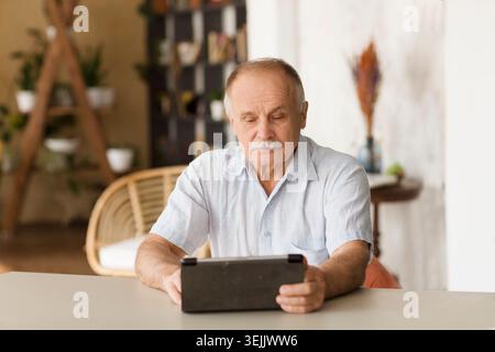 Elderly man using digital tablet  and Communicate online at home. Distancing. copy space. Stock Photo