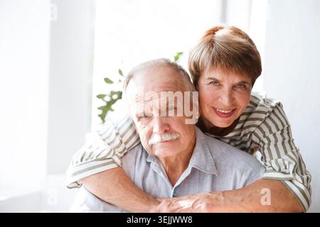 Happy Senior couple looking at camera, smiling talking at webcam saying hello hi making online call vlog in home. quarantine. he Stock Photo