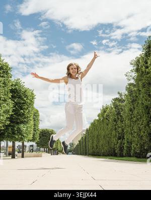 Pretty young woman jumping in the park Stock Photo