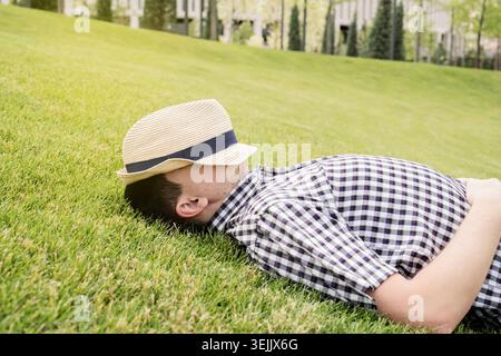 Young thoughtful man sitting on the grass in the park Stock Photo