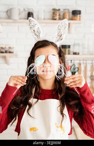 Beautiful brunette woman in rabbit ears covering eyes with easter eggs decorations Stock Photo