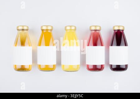 Organic fruits juices - set of different color juices with cap in glass bottles with blank label on white background, mock up fo Stock Photo