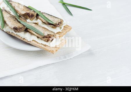 Fresh spring vitamine sandwiches of flat cereal wheat dry crisps bread with cream cheese, fish preserves, green onion on white w Stock Photo