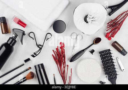 Collection of beauty products, makeup tools in stylish black  with red sprig, silver sequins purse on soft light white wooden bo Stock Photo
