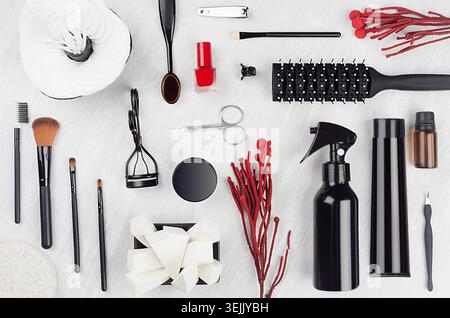 Stylish glossy black cosmetic products and mack up accessories with red twig and nail polish on soft light white wooden backgrou Stock Photo