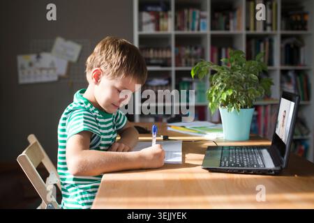 Preteen schoolboy doing his homework with laptop at home. homeschooling, distant learning Stock Photo