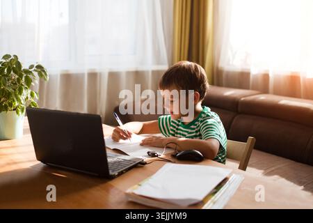 Preteen schoolboy doing his homework with laptop at home. homeschooling, distant learning Stock Photo