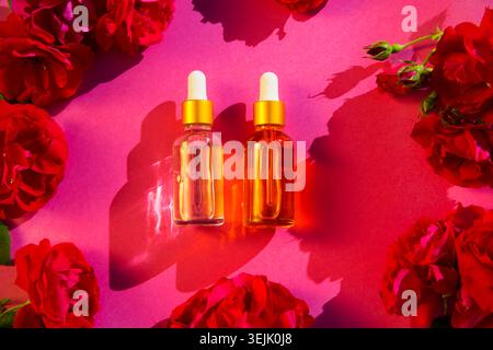 Cosmetic glass bottle  for essential oils withrose flowerson a pink background. Spa still life with Natural Serums in glass bott Stock Photo
