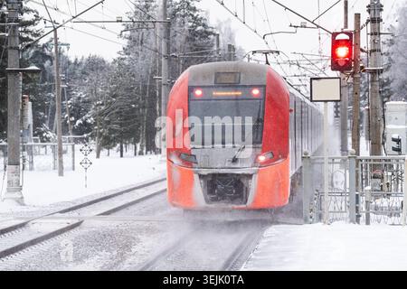 Modern high-speed electric train arriving at railway station platform at high speed on winter day Stock Photo