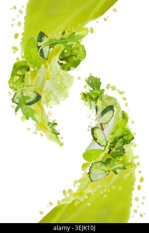 Two streams of fresh green vegetable smoothie pour and connect in air with flying green leaves, cucumber slices, vegetables, spl Stock Photo