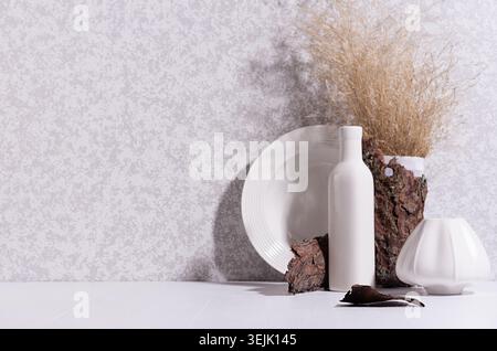Scandinavian minimalist interior with ceramic vase, dish, dried grass bouquet, brown tree bark, moss in sun beam with shadow on Stock Photo