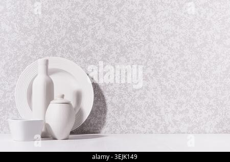 Simple minimalist home interior with white ceramic crockery - plate, bowl, pot, vase in morning sunlight with shadow on white wo Stock Photo