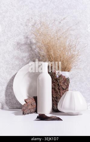 Scandinavian minimalist interior with ceramic vase, dish, dried grass bouquet, brown tree bark and moss in sun beam with shadow Stock Photo