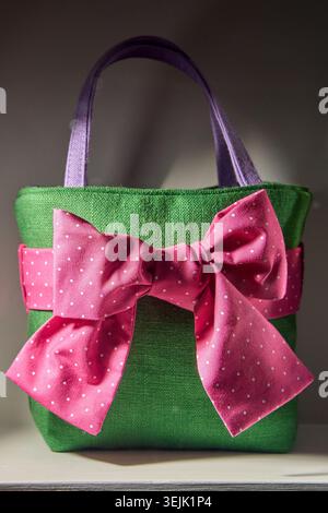 Green handmade fabric gift bag decorated with a large pink polka dot bow. Stock Photo