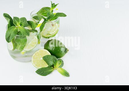 Mojito in two glasses with mint, slices lime, ice cubes, straw on soft light blue background, copy space, top view. Stock Photo