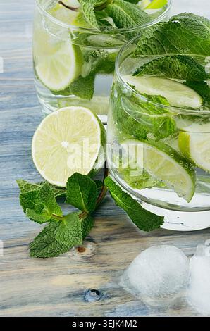 Mojito with mint, slices lime, ice cubes, straw on soft blue background, top view, closeup. Stock Photo