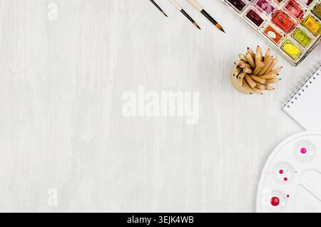 Designers workplace - stationery for creativity - watercolor paints, palette, brushes, colored pencils on white wood table, copy Stock Photo