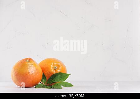 Two fresh glossy whole grapefruits on white wooden background with copy space. Stock Photo