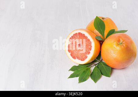 Ripe fresh orange grapefruits and half slice with green leaf on white wood board, top view. Healthy food background with copy sp Stock Photo
