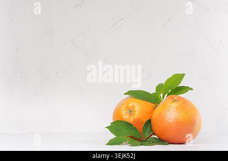 Two ripe fresh grapefruits with green leaf on light white kitchen interior. Healthy food background with copy space. Stock Photo
