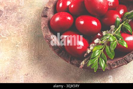 Painted eggs in a wooden bowl, red, painted madder dye, powder from the roots of endro, with onion husks, top view, Easter, Geor Stock Photo