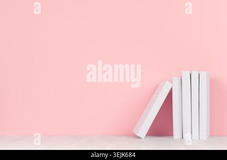 Workplace for study. Stack of white books lying on a white table and pink wall as background. Stock Photo
