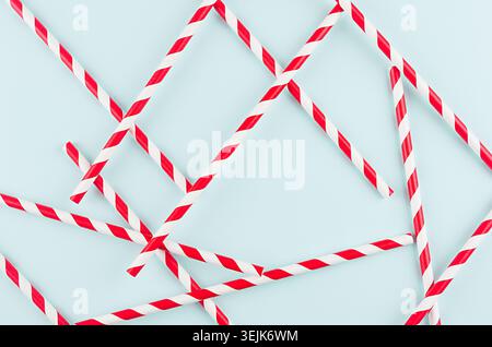 Playful trendy colors abstract background - red striped straws as pattern on mint paper backdrop. Stock Photo