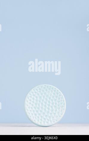 Contemporary art abstract background, interior - decorative ceramic smooth ribbed sphere in soft pastel blue color on white wood Stock Photo