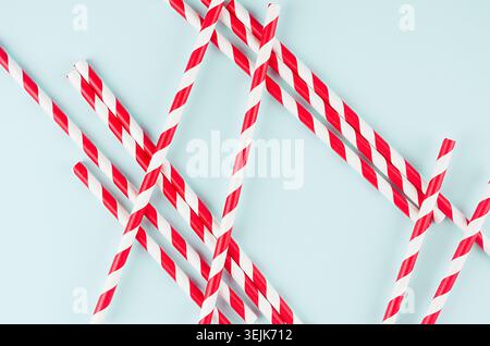 Minimalist modern art abstract background - red striped straws on light soft mint colors paper. Stock Photo