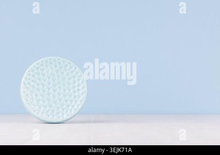 Contemporary art abstract background, interior - decorative ceramic smooth ribbed sphere in soft pastel blue color on white wood Stock Photo