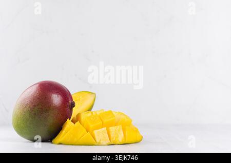 Juicy mango with ripe yellow sliced half on soft light white wood background. Elegant moder kitchen interior with tropical fruit Stock Photo