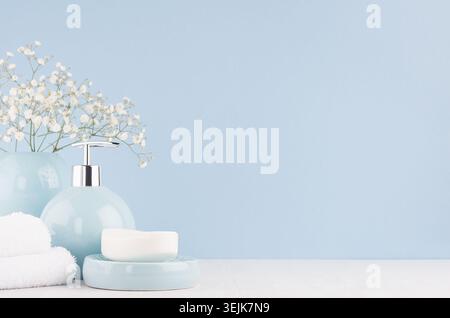 Bathroom interior - ceramic accessories - light blue circle vase with white flowers, soap dispenser , fluffy towels on white woo Stock Photo