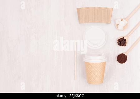 Coffee design concept mockup - brown paper cup with blank  label, cap, spoons with sugar and beans on white wood board, top view Stock Photo
