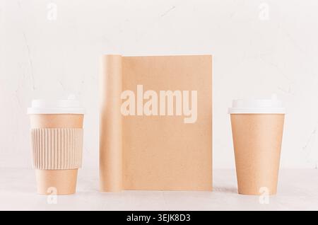 Eco friendly coffee template for design, advertising and branding - two brown paper cups and blank notebook on white wood shelf. Stock Photo