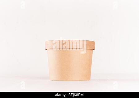 Blank disposable brown paper box for takeaway food - soup, salad, ice cream on white wood shelf closeup, mockup food  packaging Stock Photo