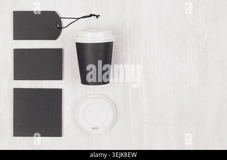 Coffee takeaway set mockup for brand - black paper cup, blank card, label, white cap on white wood board, copy space, top view. Stock Photo